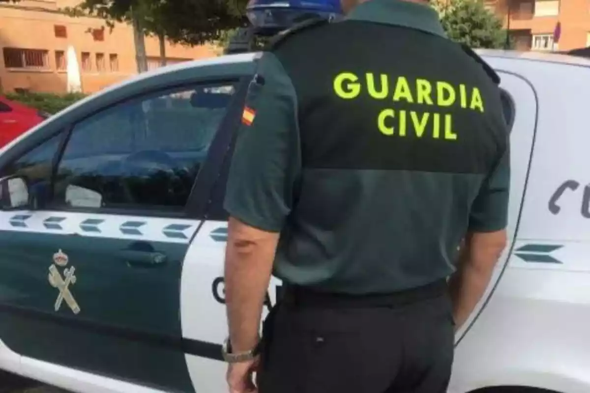 Agente de la Guardia Civil junto a su coche