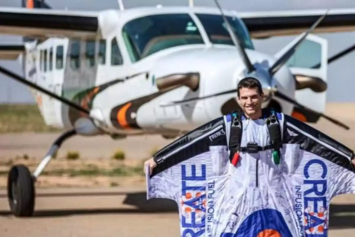 Álex Villar delante de una avioneta con su traje de salto