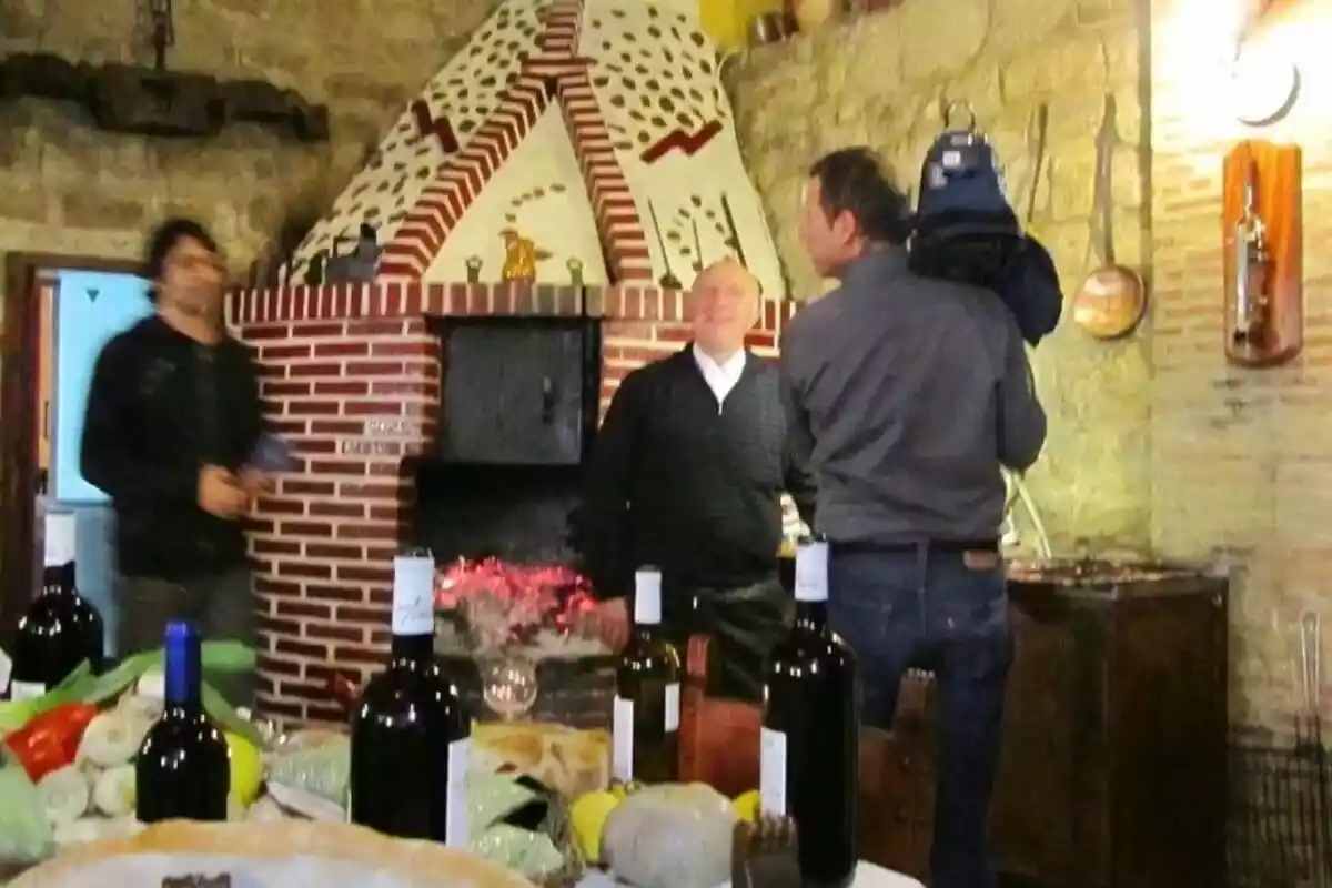 Foto del restaurante 'La Bodega Guillermo de Cuzcurrita' con una mesa con vino y tres hombres