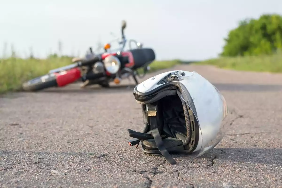 Imagen de un casco y una moto tiradas en el suelo tras un accidente