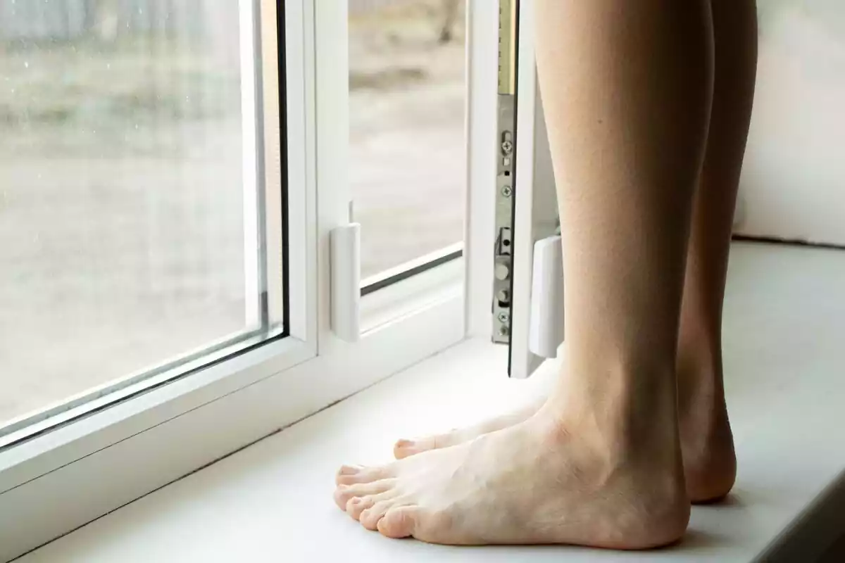 Imagen de unos pies enfrente de la ventana de un baño