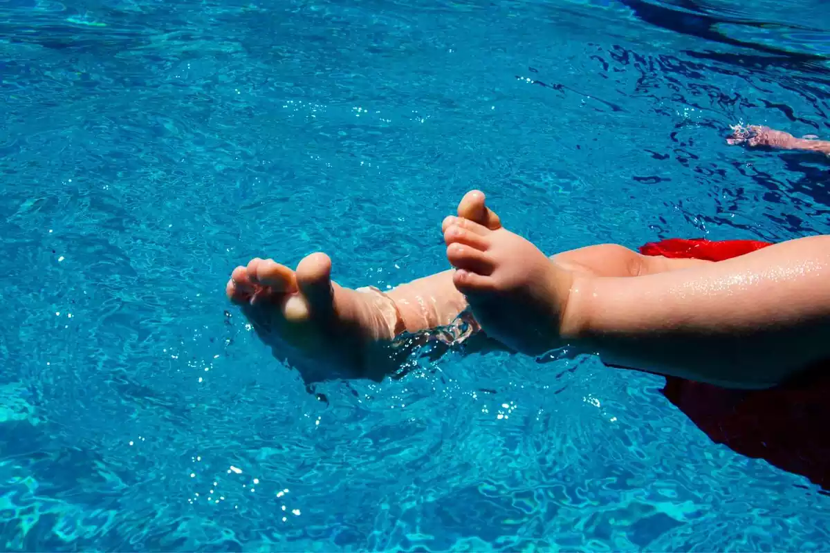 Pies de un bebé sumergidos en el agua de una piscina