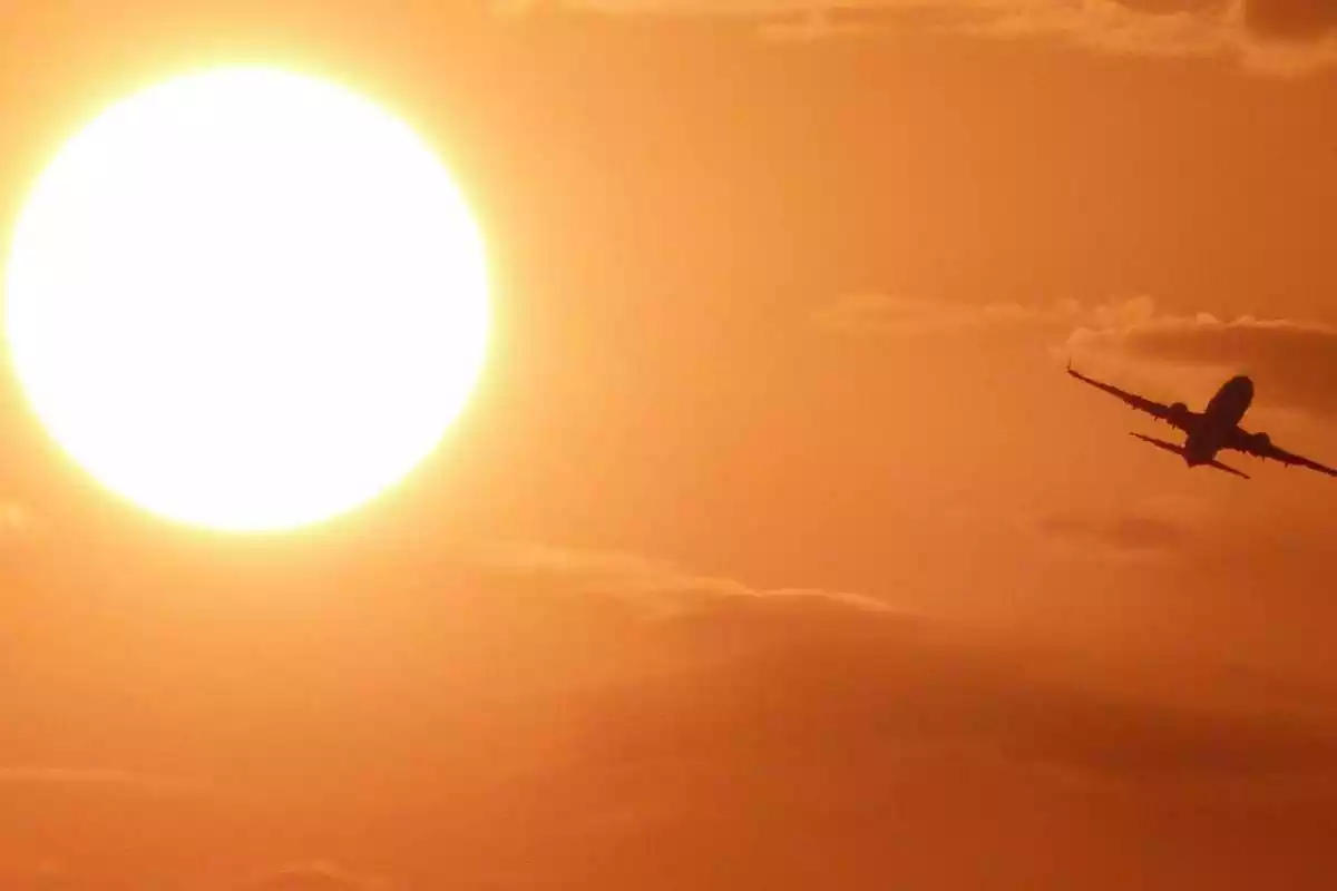 Imagen de un avión volando bajo el sol del amanecer en el Mediterráneo