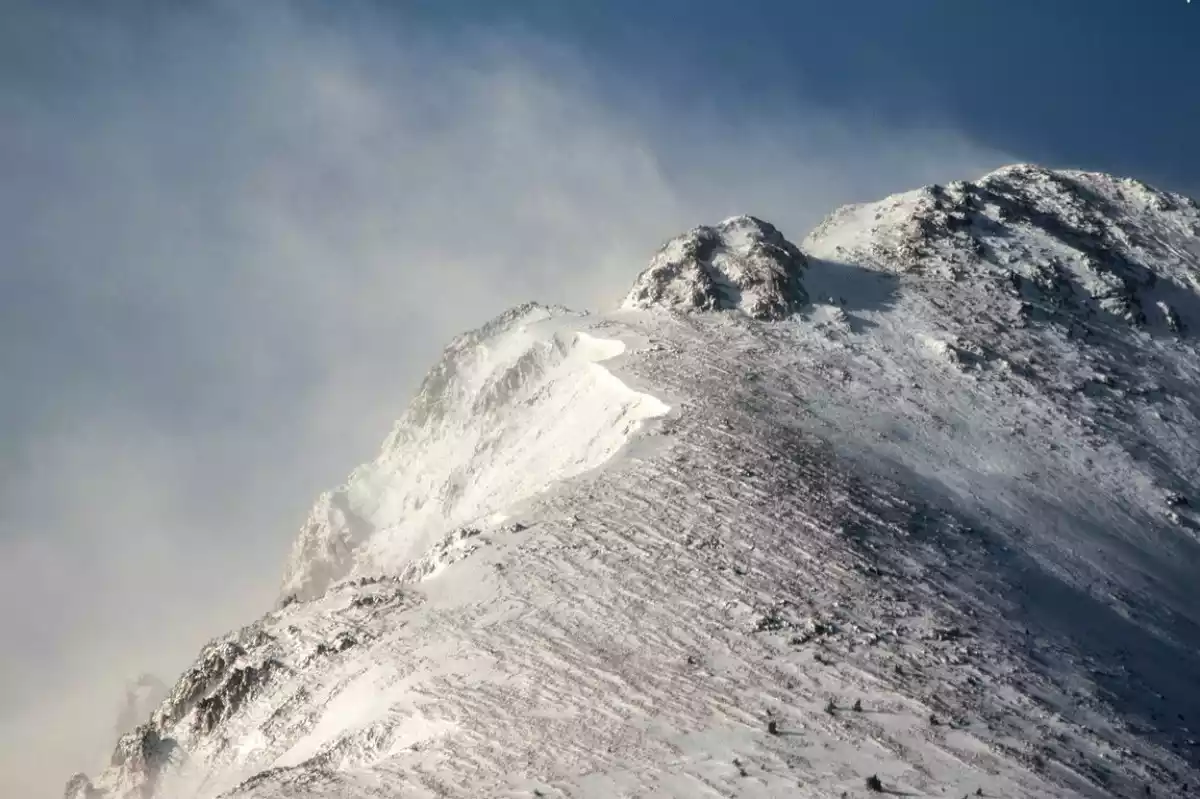 Imagen de una montaña nevada del Pirineo con ventisca en las cumbres