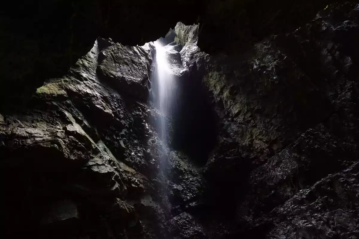 Interior de una cueva con un torrente de agua saliendo a mucha presión