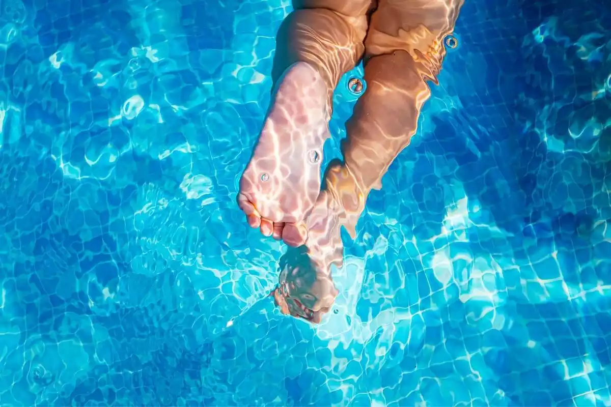 Los pies de un niño nadando en una piscina