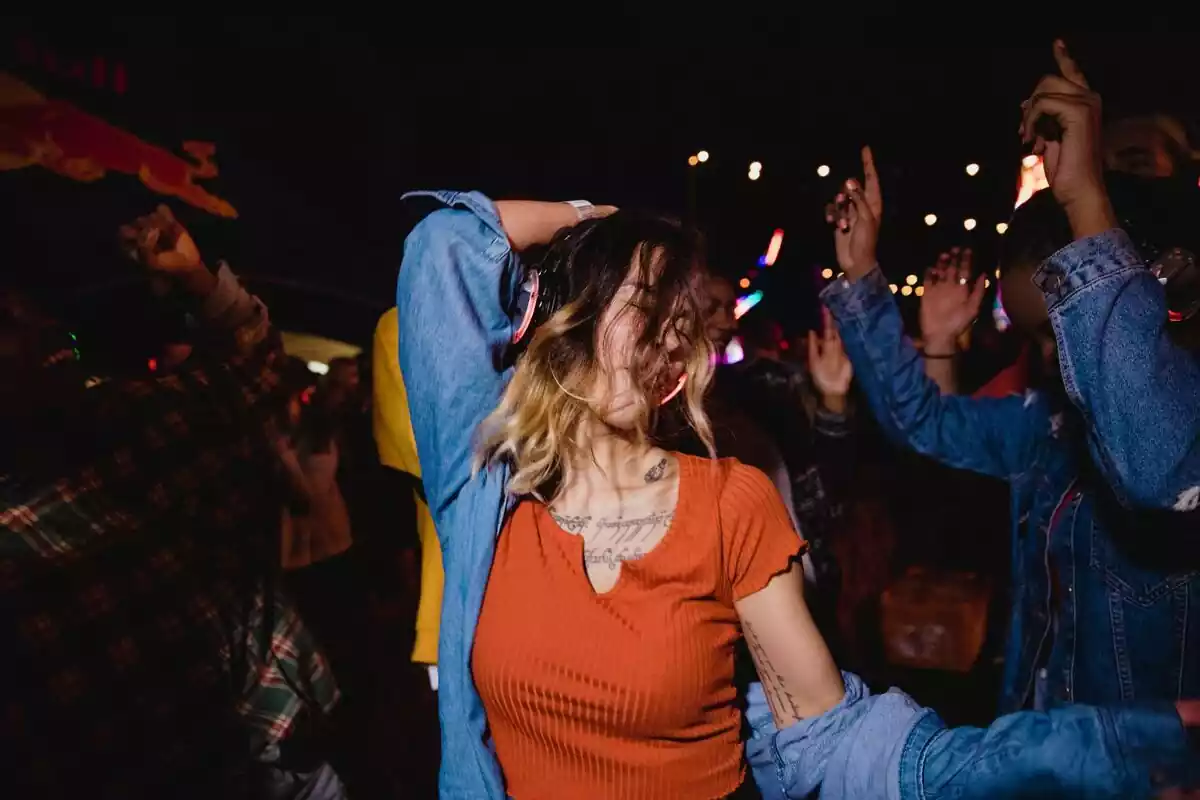 Mujer bailando en una fiesta mientras escucha música con unos cascos