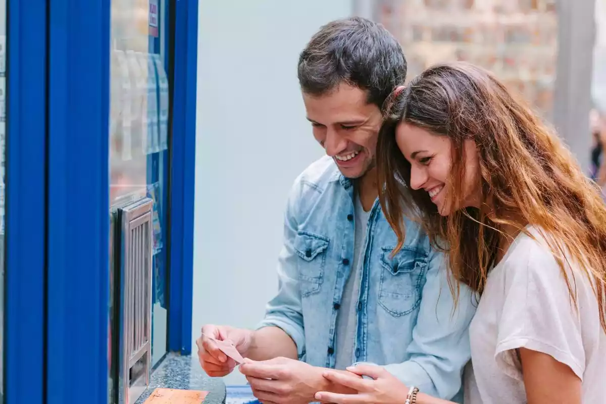 Una pareja sonriendo al comprar un billete de lotería