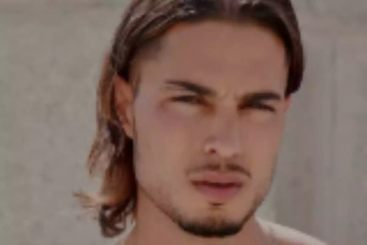 Un hombre con cabello largo y barba mirando hacia la cámara.