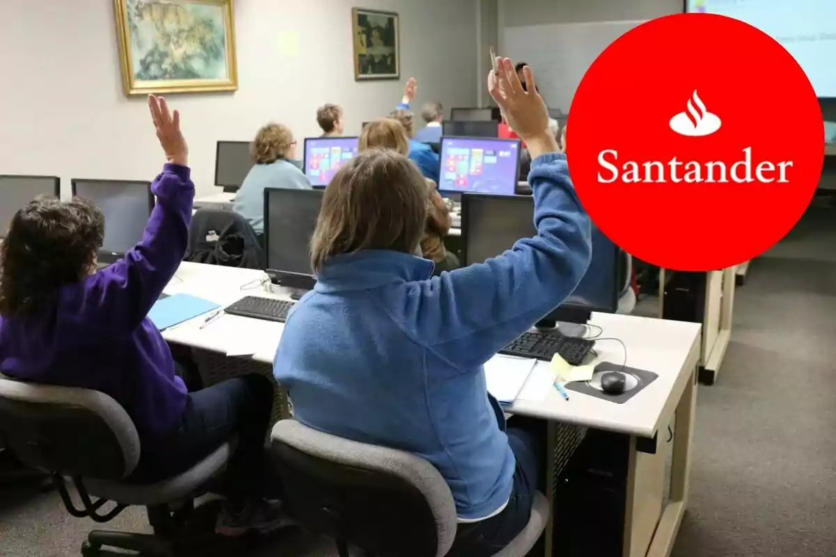 Personas en una sala de ordenadores levantan la mano mientras miran una pantalla, con un logotipo de Santander superpuesto. Personas en una sala de ordenadores levantan la mano mientras miran una pantalla, con un logotipo de Santander superpuesto.